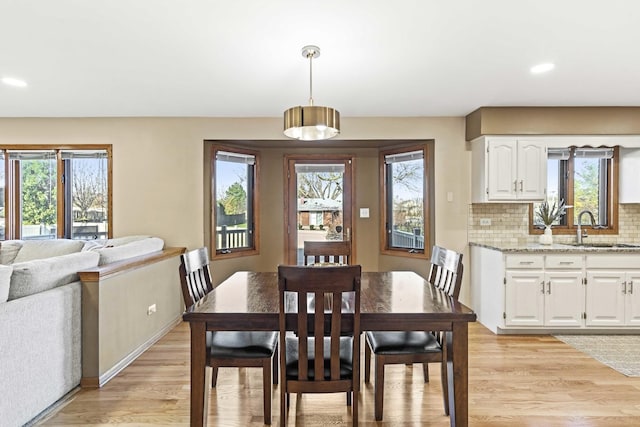 dining area with plenty of natural light, sink, and light wood-type flooring