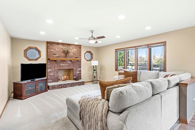 living room featuring ceiling fan, a fireplace, and light carpet