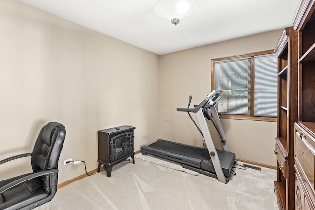 exercise area featuring a wood stove and light colored carpet