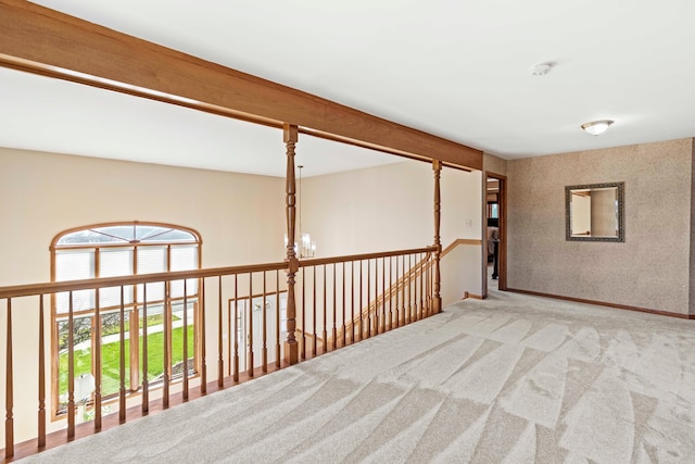 corridor with beam ceiling, a chandelier, and carpet