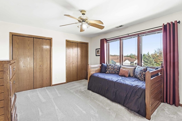 carpeted bedroom with two closets and ceiling fan