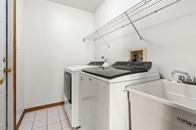 clothes washing area featuring washer and clothes dryer, sink, and light tile patterned floors