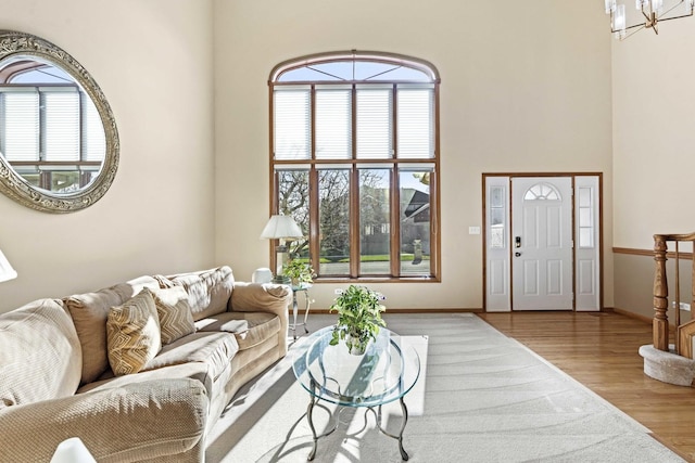 living room featuring wood-type flooring, a wealth of natural light, a chandelier, and a high ceiling