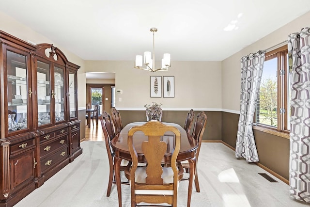 dining space featuring light colored carpet and a notable chandelier