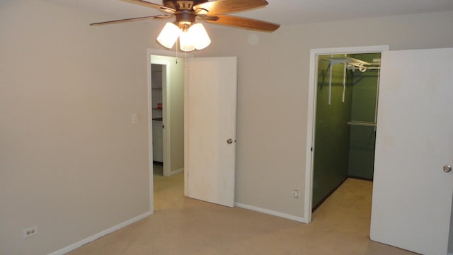 unfurnished bedroom featuring ceiling fan, a walk in closet, light carpet, and a closet