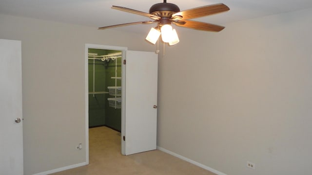 unfurnished bedroom featuring ceiling fan, a walk in closet, light carpet, and a closet