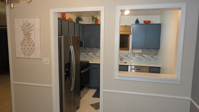 kitchen featuring decorative backsplash, light tile patterned floors, stainless steel appliances, and blue cabinets