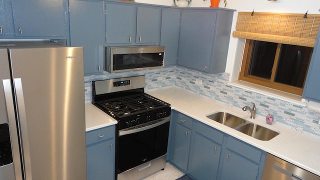 kitchen featuring blue cabinetry, decorative backsplash, sink, and stainless steel appliances