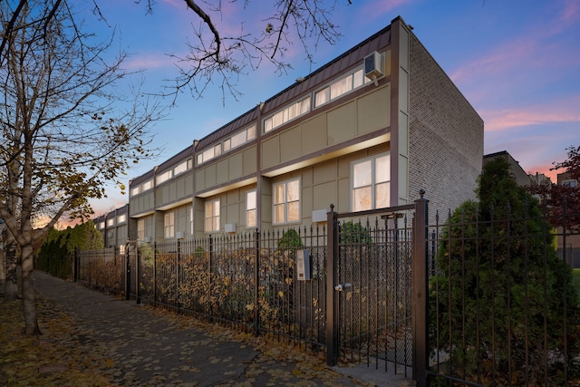 property exterior at dusk featuring a wall mounted air conditioner