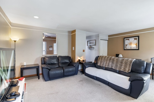 carpeted living room with ceiling fan and ornamental molding