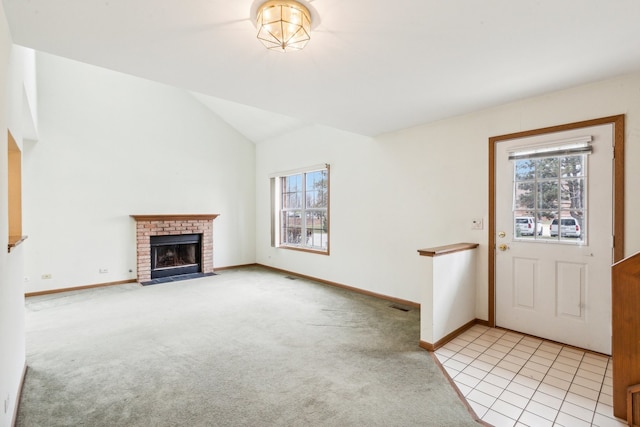 unfurnished living room featuring lofted ceiling, light colored carpet, a brick fireplace, and a healthy amount of sunlight