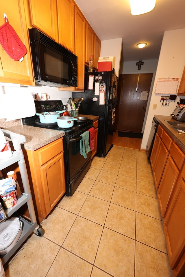 kitchen with sink, light tile patterned floors, and black appliances