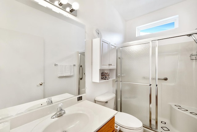 bathroom with a shower with door, vanity, and toilet