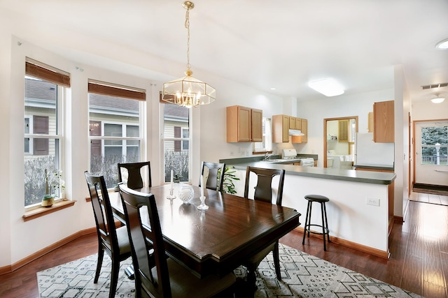 dining room featuring a notable chandelier, plenty of natural light, dark hardwood / wood-style floors, and washer / clothes dryer