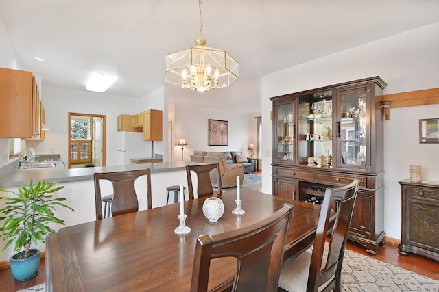 dining space featuring wood-type flooring, an inviting chandelier, and sink