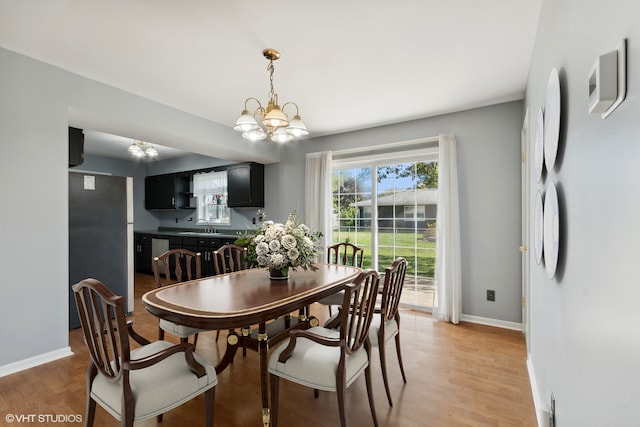 dining room with sink, wood-type flooring, and an inviting chandelier