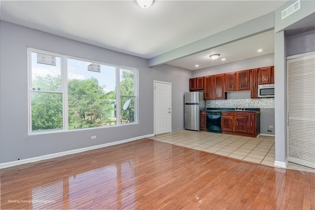 kitchen with decorative backsplash, appliances with stainless steel finishes, sink, beamed ceiling, and light hardwood / wood-style floors