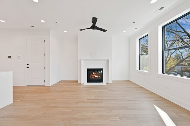 unfurnished living room with ceiling fan, light wood-type flooring, and crown molding