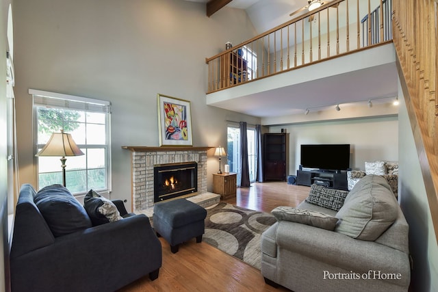 living room with a fireplace, hardwood / wood-style floors, rail lighting, and a high ceiling