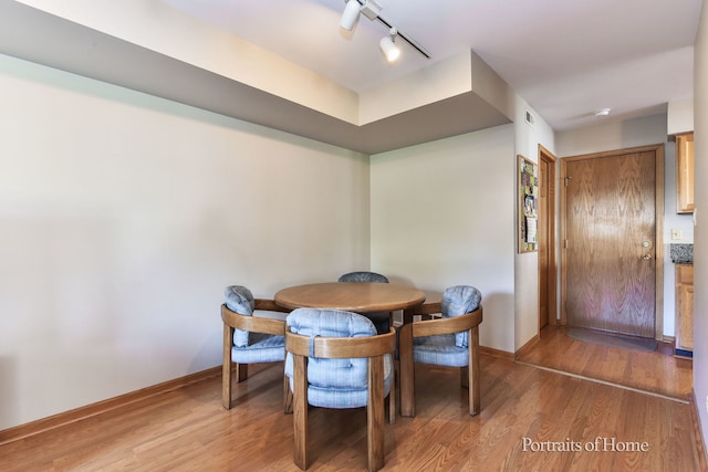 dining space with rail lighting and hardwood / wood-style floors