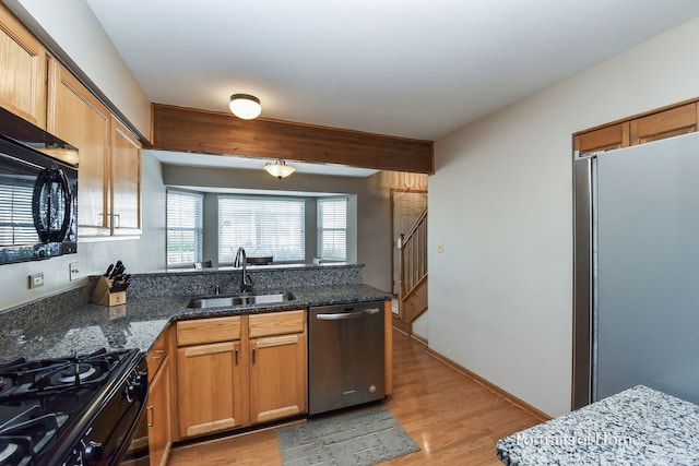 kitchen featuring light hardwood / wood-style flooring, sink, dark stone countertops, and black appliances