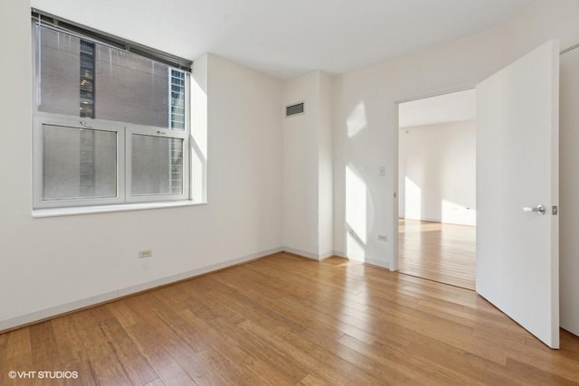 unfurnished room with light wood-style flooring, visible vents, and baseboards