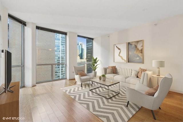 living room featuring expansive windows, baseboards, and light wood-style floors