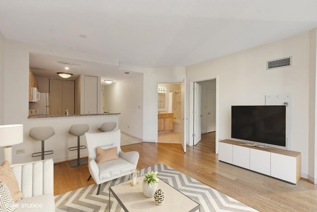 living room with visible vents, light wood-style flooring, and baseboards