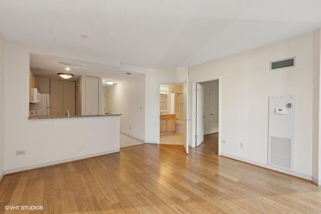 unfurnished living room featuring light wood-style floors, baseboards, and visible vents