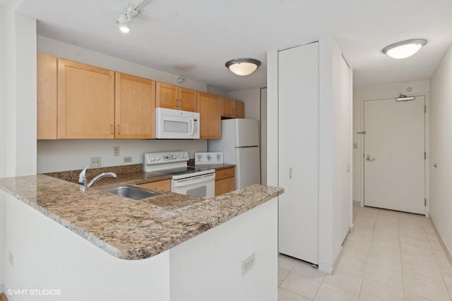 kitchen with a peninsula, white appliances, a sink, and light stone counters