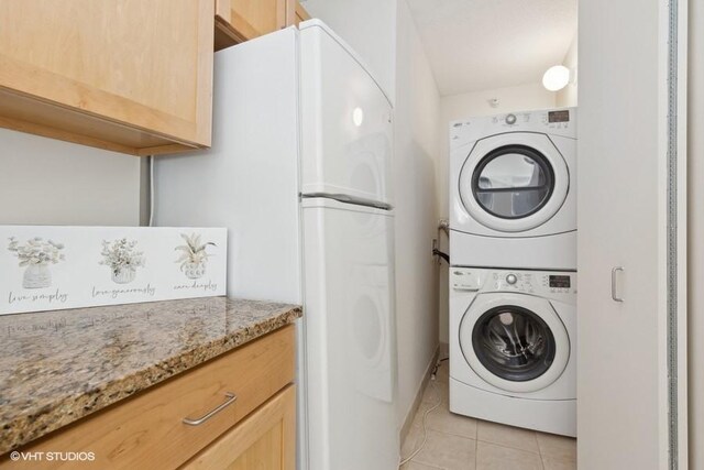 laundry area featuring laundry area, stacked washer / dryer, and light tile patterned flooring