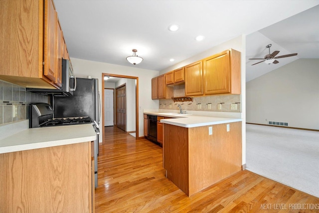 kitchen featuring black appliances, light hardwood / wood-style floors, lofted ceiling, and kitchen peninsula