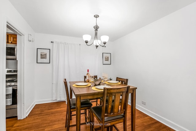 dining space featuring wood-type flooring and an inviting chandelier