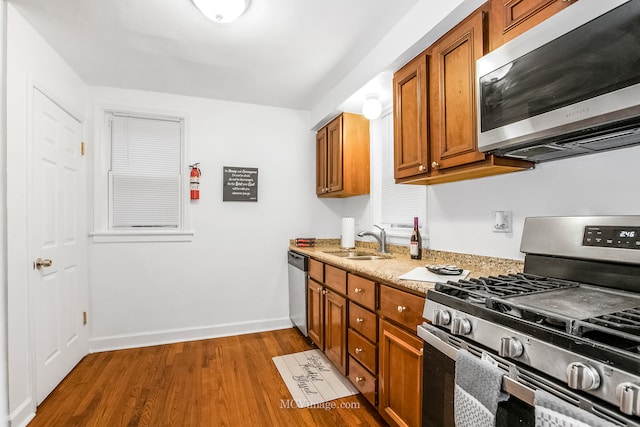 kitchen featuring appliances with stainless steel finishes, light stone counters, dark wood-type flooring, and sink