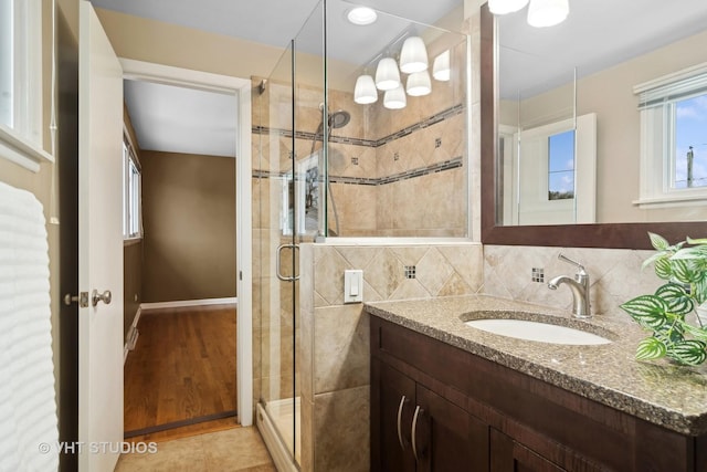 bathroom with tasteful backsplash, tile patterned flooring, vanity, and walk in shower