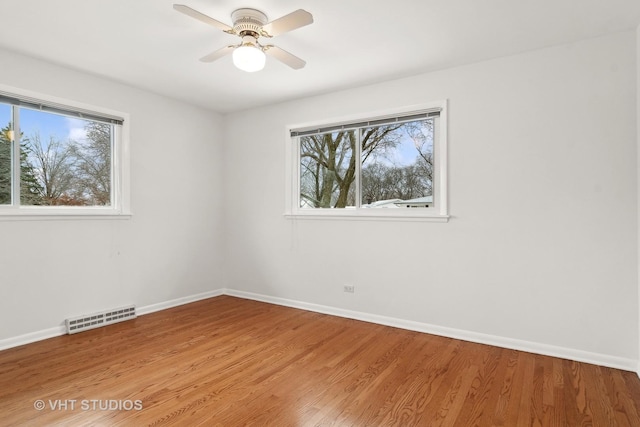 empty room with hardwood / wood-style floors, a wealth of natural light, and ceiling fan