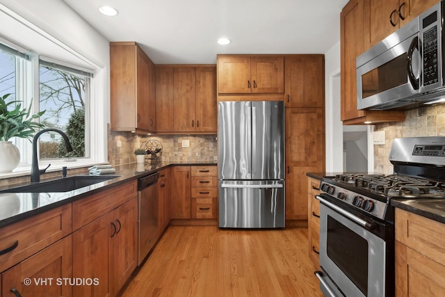 kitchen featuring decorative backsplash, appliances with stainless steel finishes, light wood-type flooring, and sink