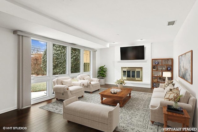 living room featuring dark wood-type flooring and a brick fireplace