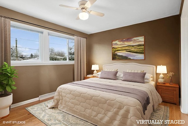 bedroom featuring baseboard heating, ceiling fan, and light wood-type flooring