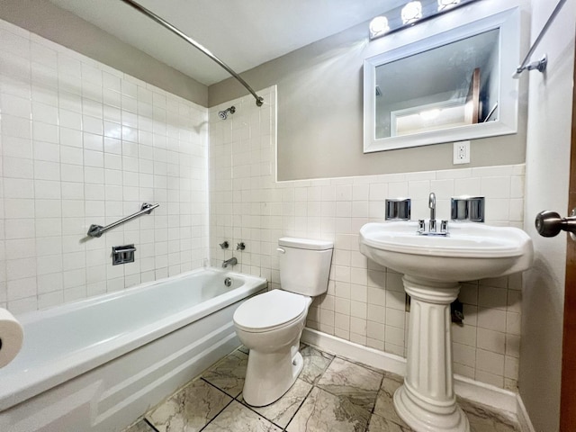 full bathroom with sink, tiled shower / bath combo, toilet, and tile walls