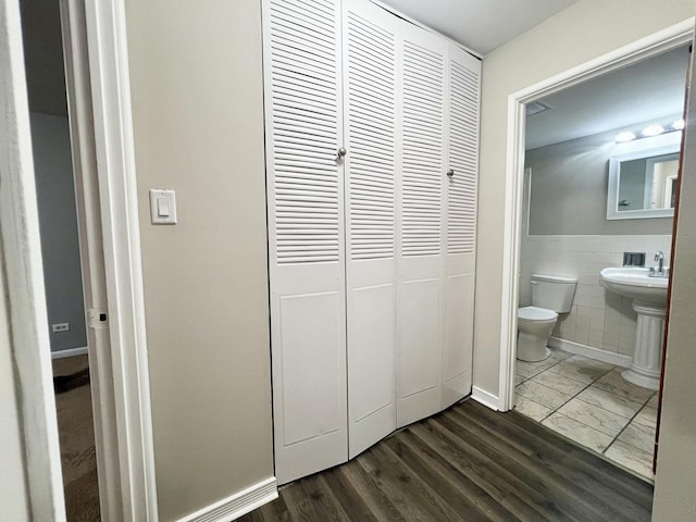 bathroom featuring sink, wood-type flooring, tile walls, and toilet