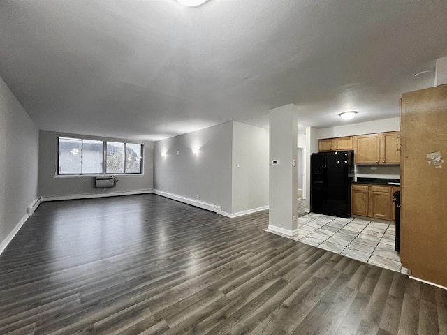 unfurnished living room featuring baseboard heating, light hardwood / wood-style flooring, and a wall mounted air conditioner