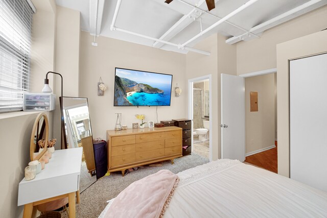 carpeted bedroom with ensuite bath, ceiling fan, and beamed ceiling