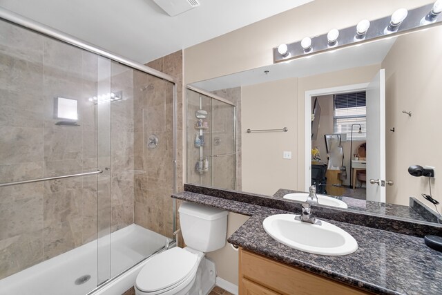 bathroom with vanity, toilet, and a shower with door