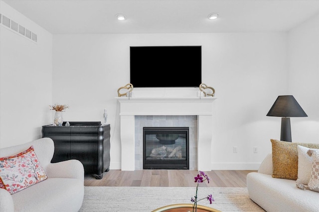 living area featuring baseboards, visible vents, wood finished floors, a fireplace, and recessed lighting