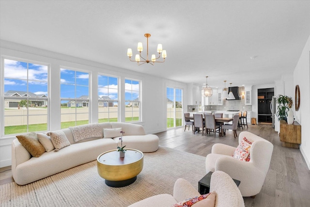 living room featuring light wood-type flooring, an inviting chandelier, a residential view, and baseboards