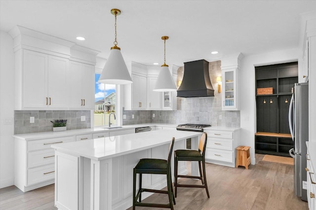 kitchen with a kitchen island, white cabinets, light countertops, glass insert cabinets, and custom range hood