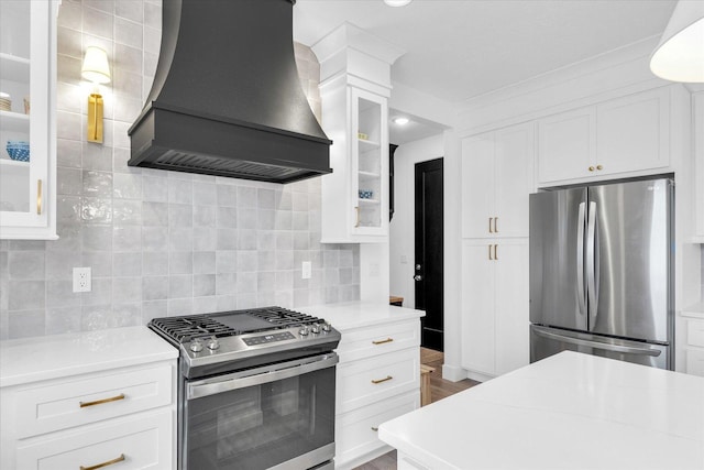 kitchen featuring light countertops, appliances with stainless steel finishes, glass insert cabinets, and custom range hood