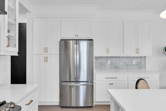 kitchen with open shelves, light stone counters, freestanding refrigerator, and white cabinetry