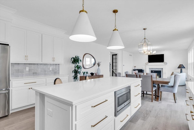 kitchen with tasteful backsplash, appliances with stainless steel finishes, a center island, white cabinetry, and pendant lighting